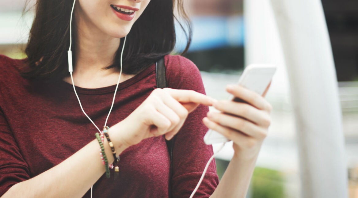 Frau hört mit Kopfhörern Musik auf dem Smartphone