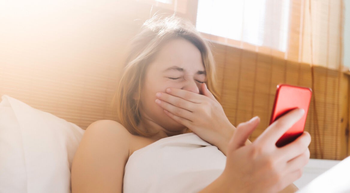 Frau im Bett mit Heuschnupfen am Handy