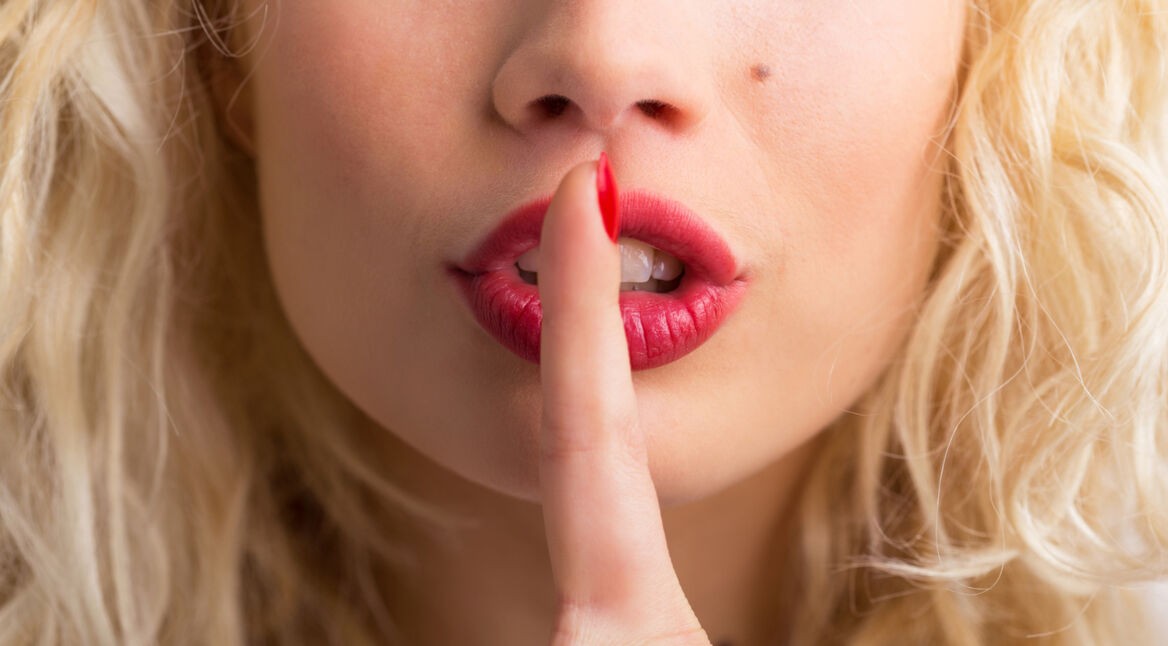 Frau hält den Finger auf ihre Lippen