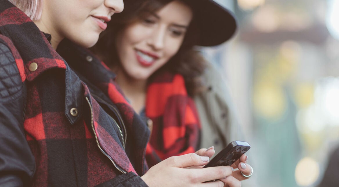 Zwei Frauen gucken auf ein Smartphone.