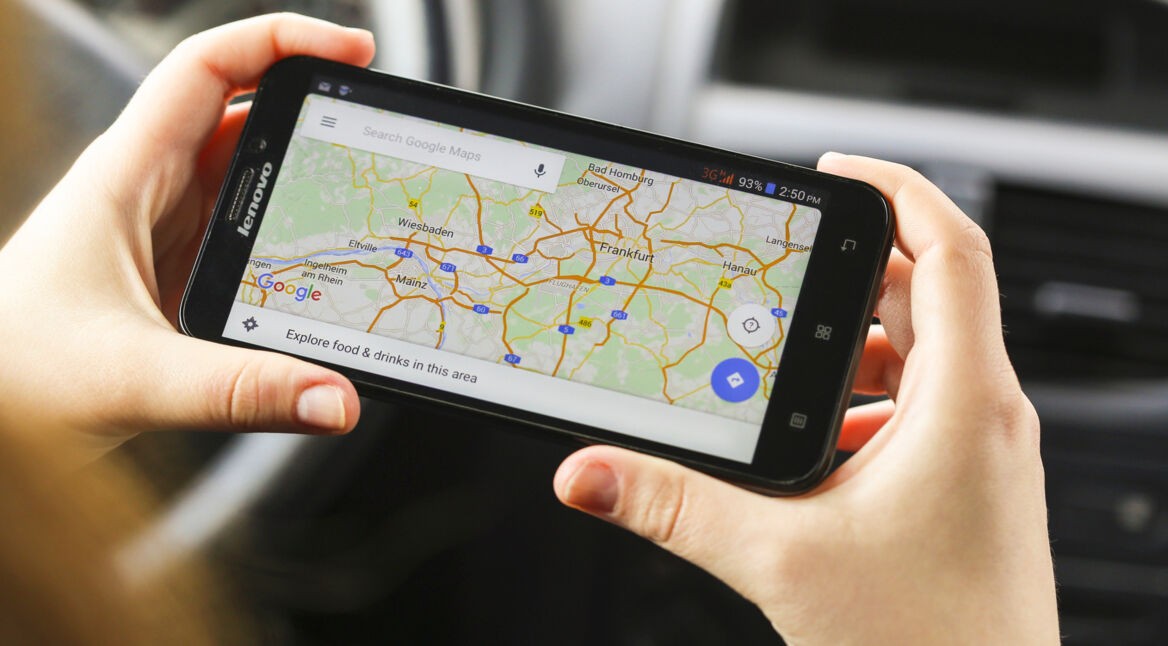Frau im Fahrzeug mit Google Maps auf dem Smartphone