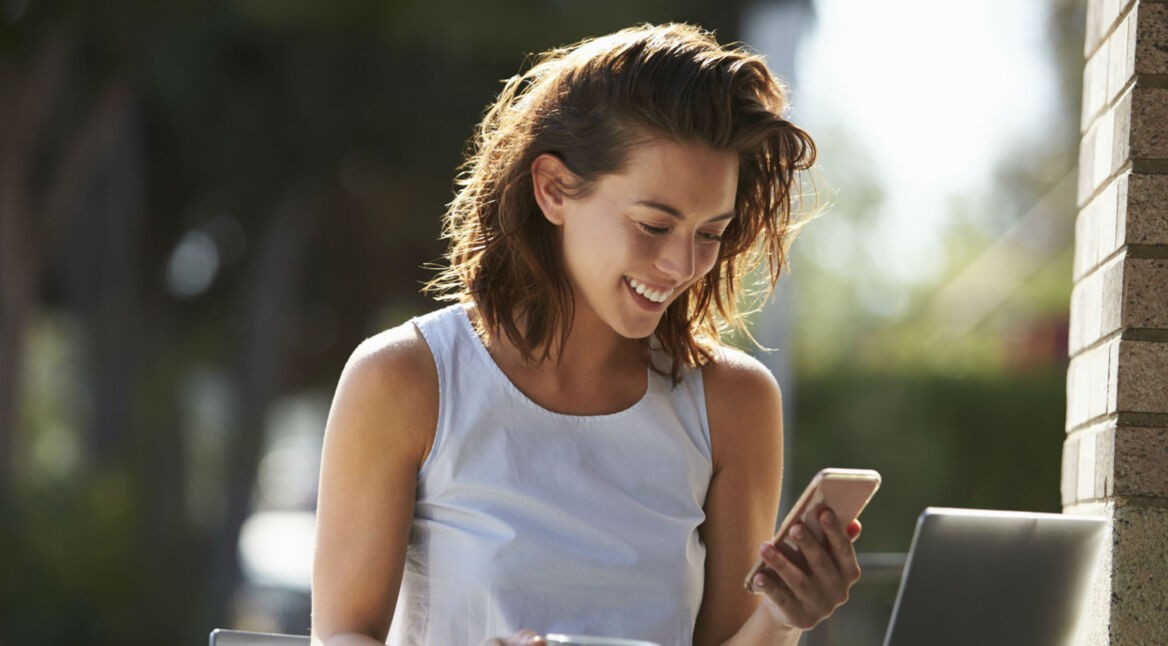 Frau freut sich über Facebook-Postings von Freunden