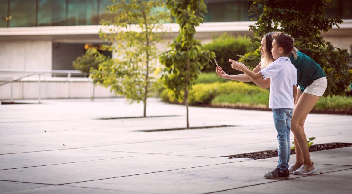 Junge Frau und Kind betrachten Betonwüste durch ein Smartphone
