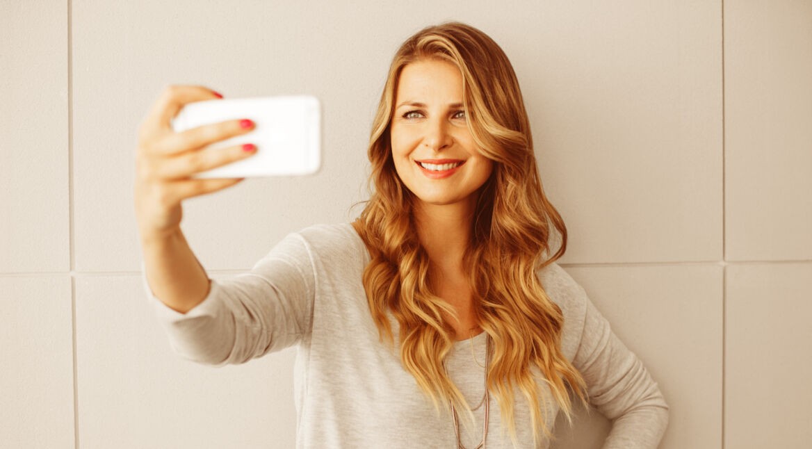 Frau schaltet Smartphone mit Gesichtserkennung frei.