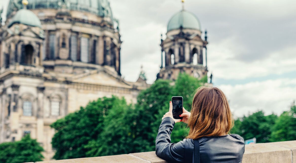 Frau schießt ein Foto vom Berliner Dom mit dem Smartphone