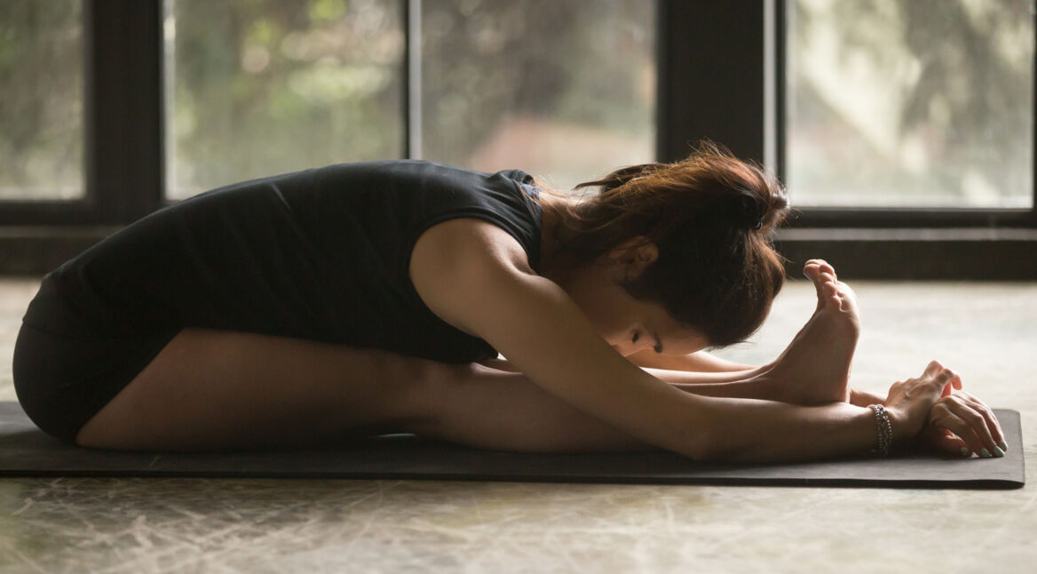 Frau macht Yoga und liegt zusammengefaltet