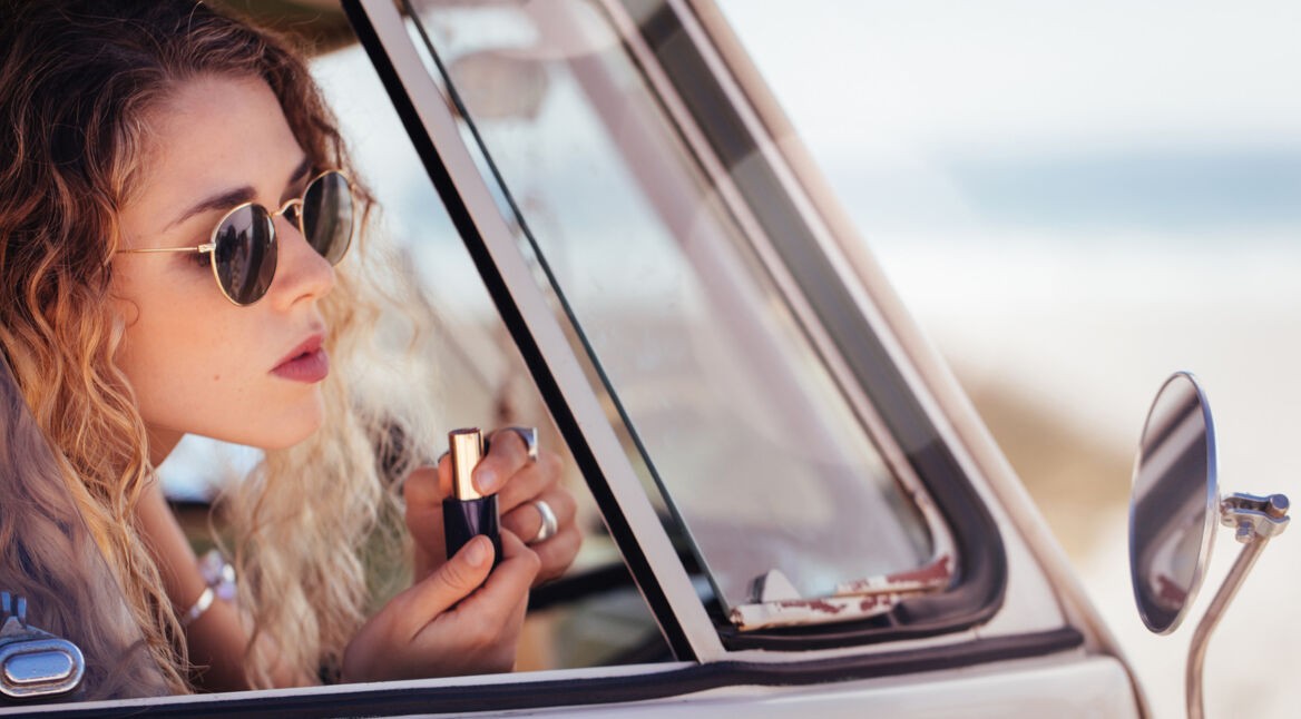 Frau mit Lippenstift unterwegs beim Schminken