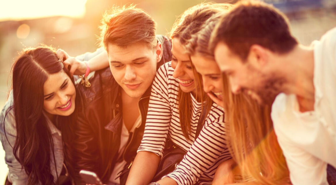 Gruppe von Freunden guckt aufs Smartphone