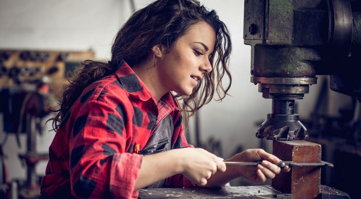 Junge Frau arbeitet in der Werkstatt.