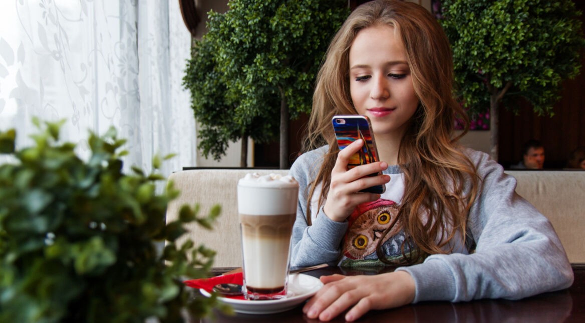 Junge Frau nutzt Facebook auf dem Handy