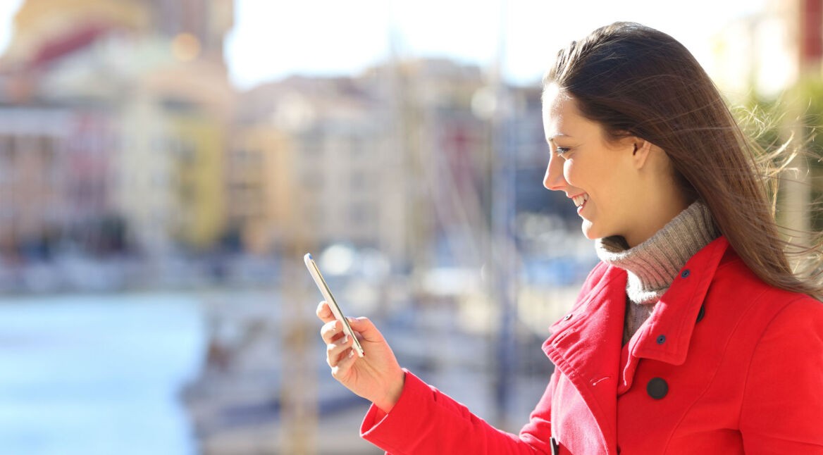 Frau im roten Mantel schaut auf ihr Smartphone