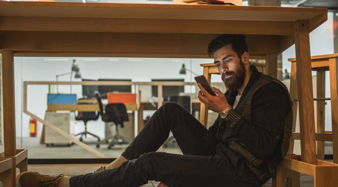 Mann unterm Tisch versteckt seine WhatsApp-Kontakte