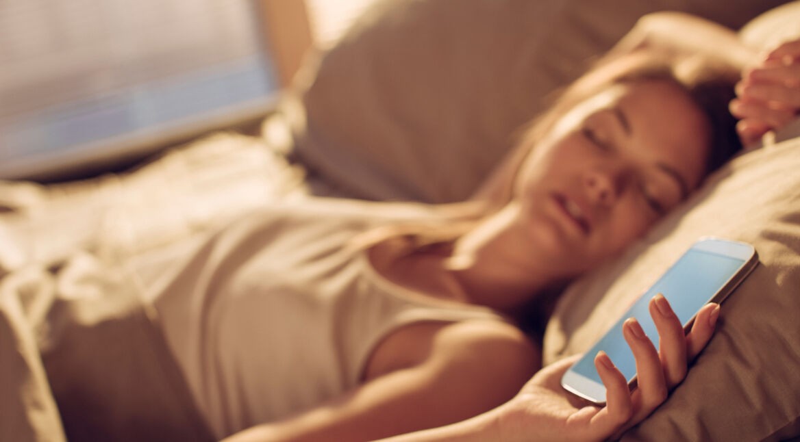 Frau schläft neben Smartphone mit Android Oreo.