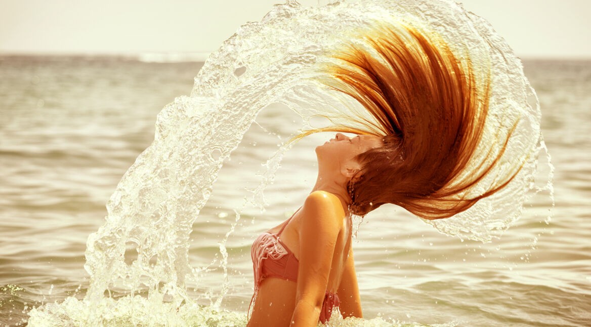 Frau wirft Haare schwungvoll nach hinten.