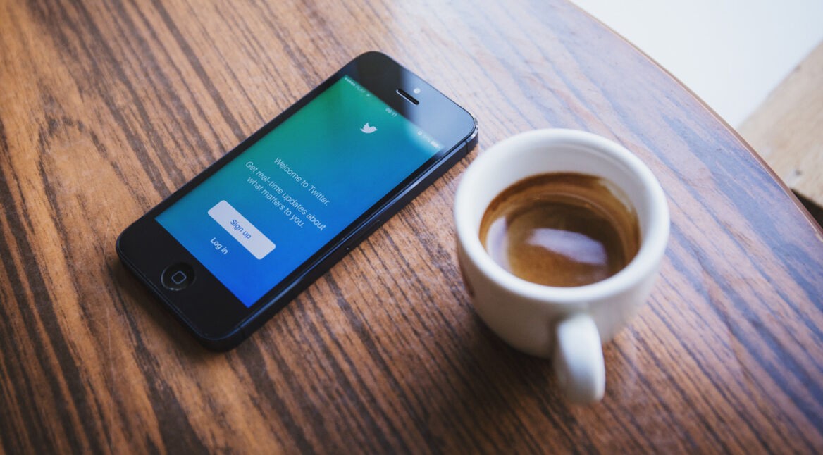 Smartphone auf dem Tisch mit Twitter-Oberfläche und Kaffee