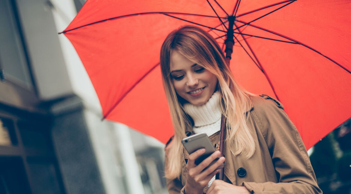 Frau mit Regenschirm und Smartphone