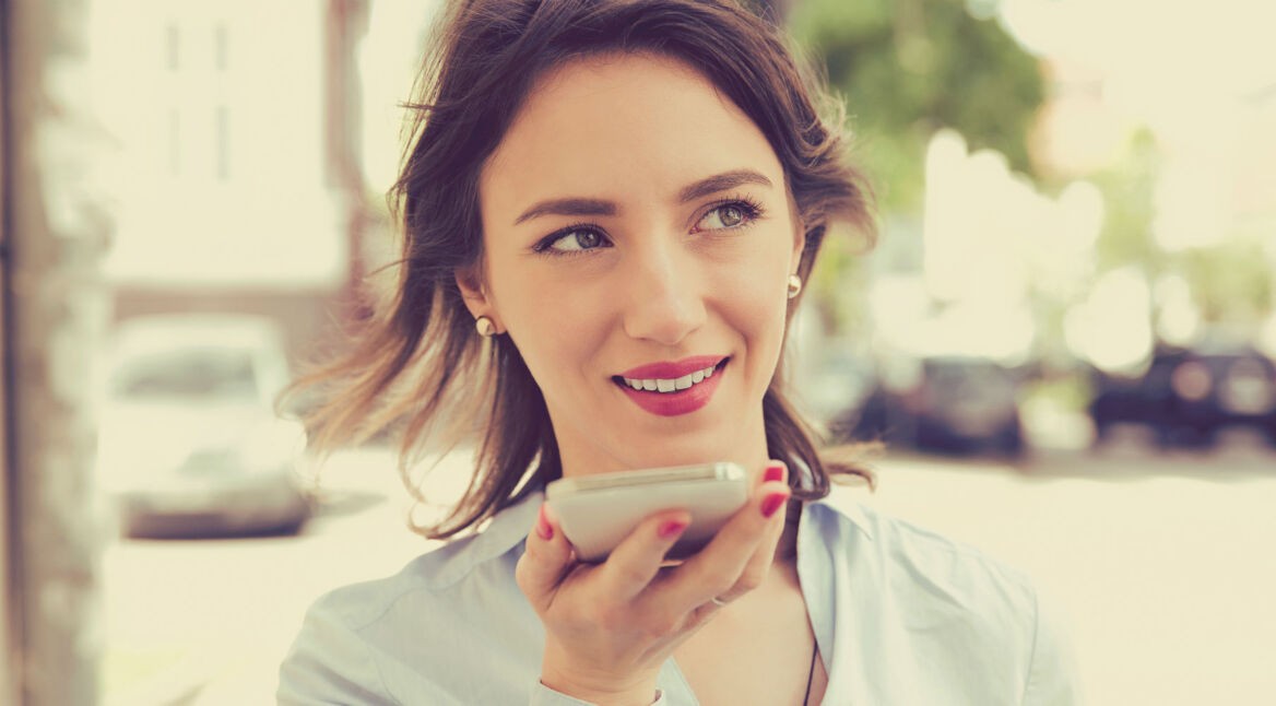 Frau spricht mit dem Sprachassistenten des Smartphones.