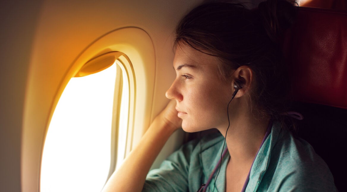 Frau im Flugzeug schaut entspannt aus dem Fenster