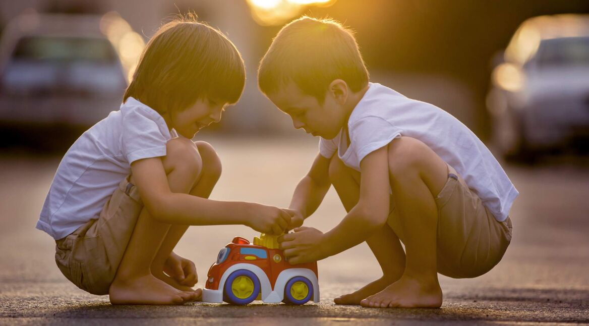 Two sweet children, boy brothers, playing with car toys
