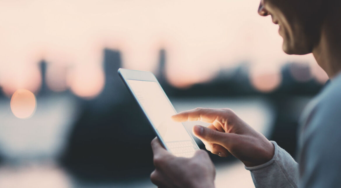 Junger Mann hält ein Tablet in der Hand.