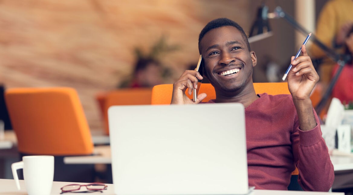 Junger Mann telefoniert lächelnd mit dem Android-Smartphone.