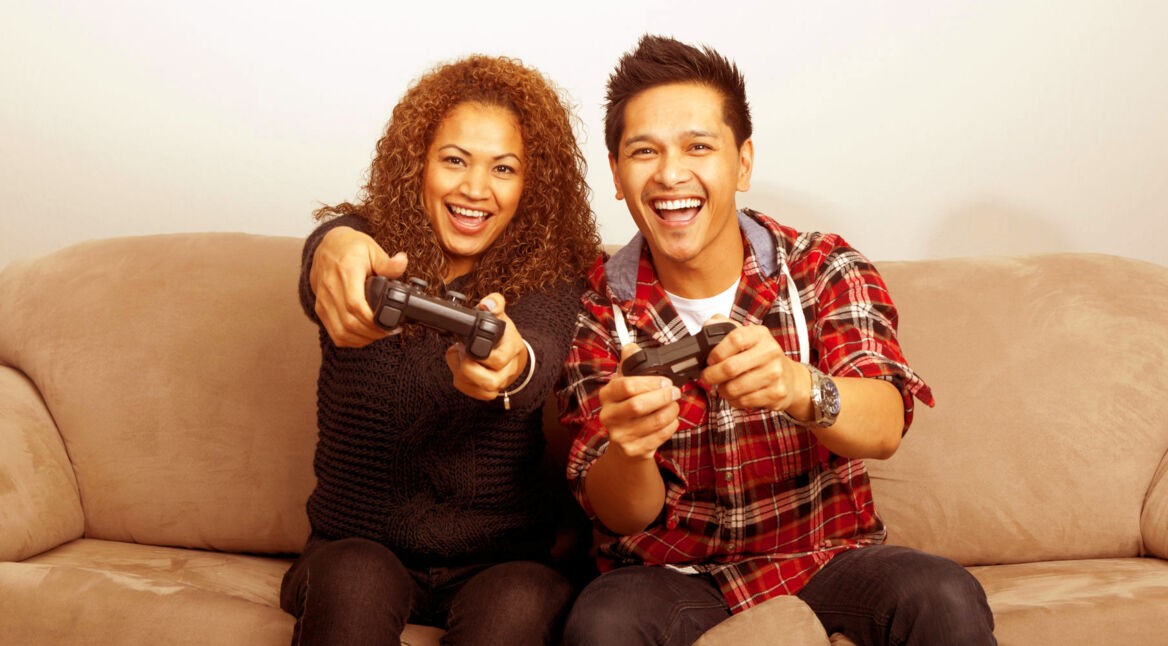 Paar auf dem Sofa spielt mithilfe von Controllern.