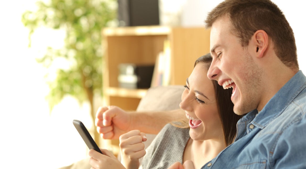 Ein Paar freut sich über gewonnene Auktion am Smartphone