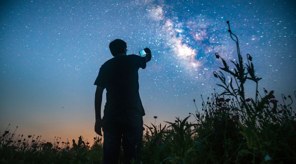 Mann fotografiert die Sterne mit dem Handy.