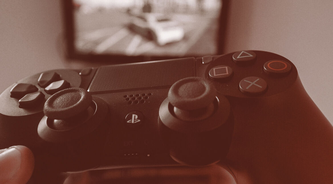 Schwarzer PlayStation 4-Controller vor Fernseher.