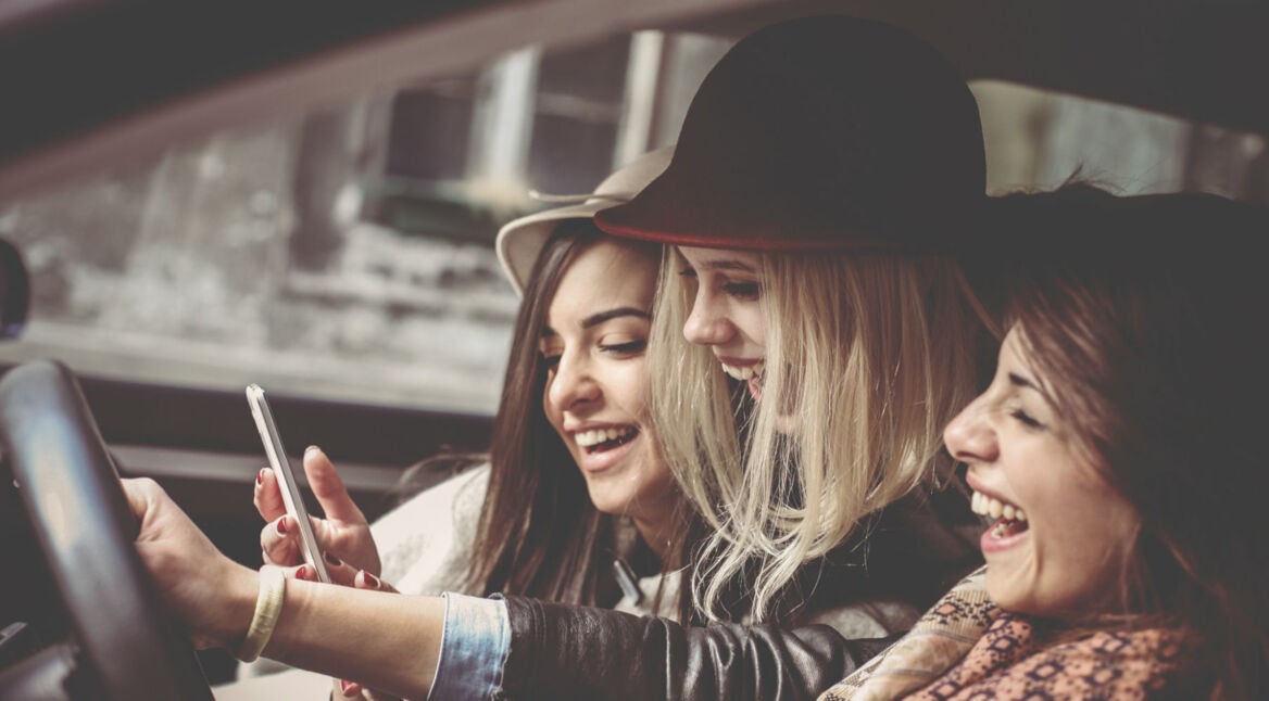 Drei Freundinnen lachen zusammen.