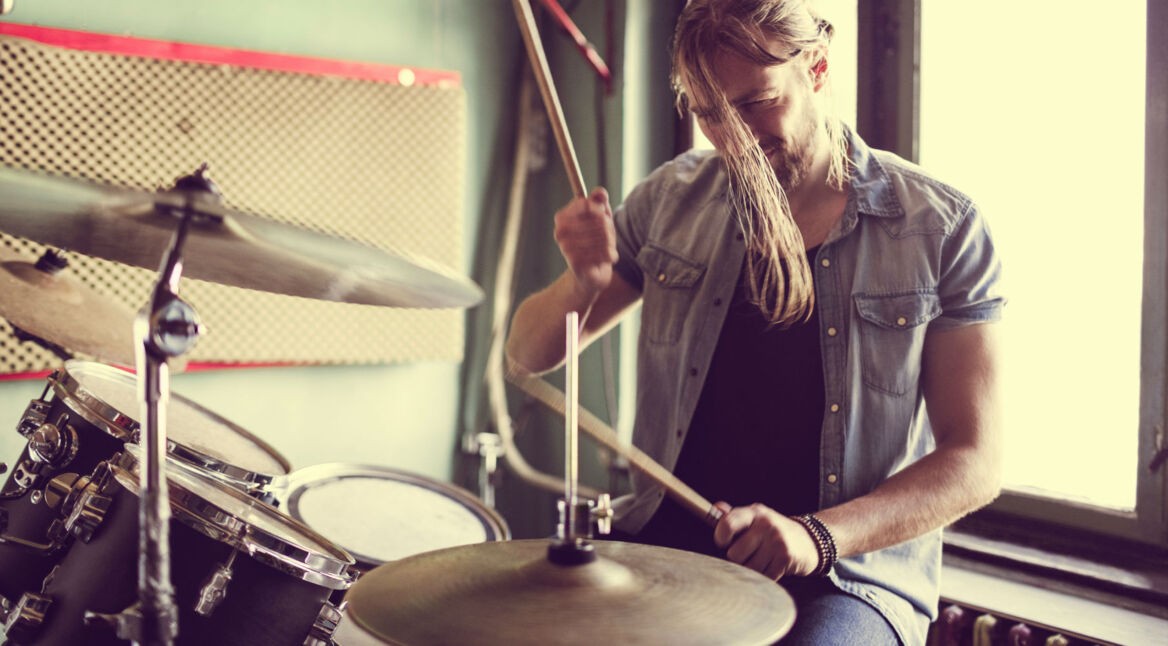 Junger Mann trommelt auf einem Schlagzeug herum.