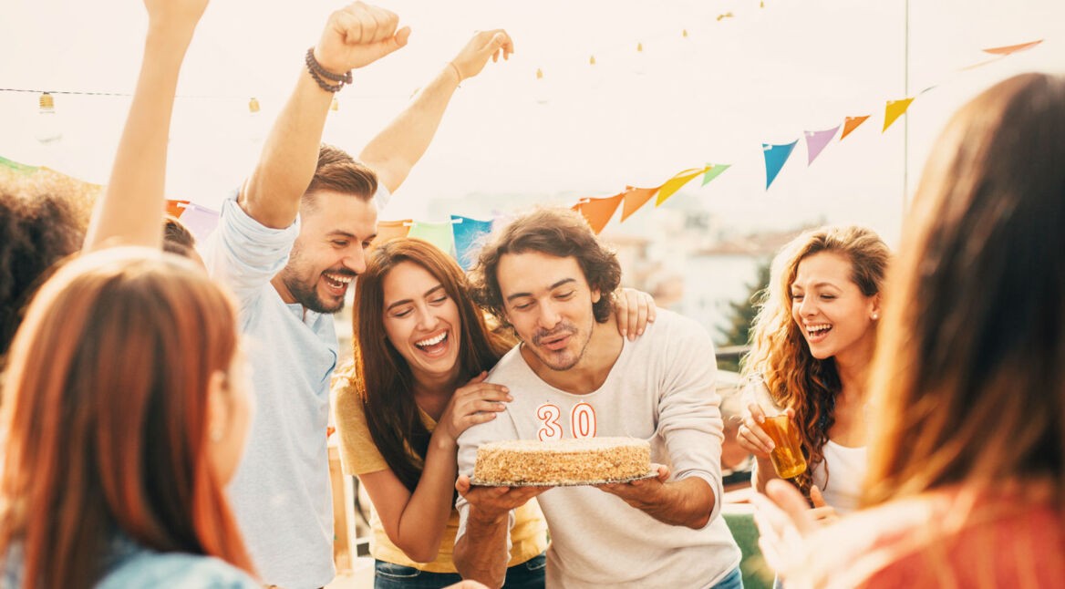 Freunde feiern einen Geburtstag mit Geburtstagstorte.