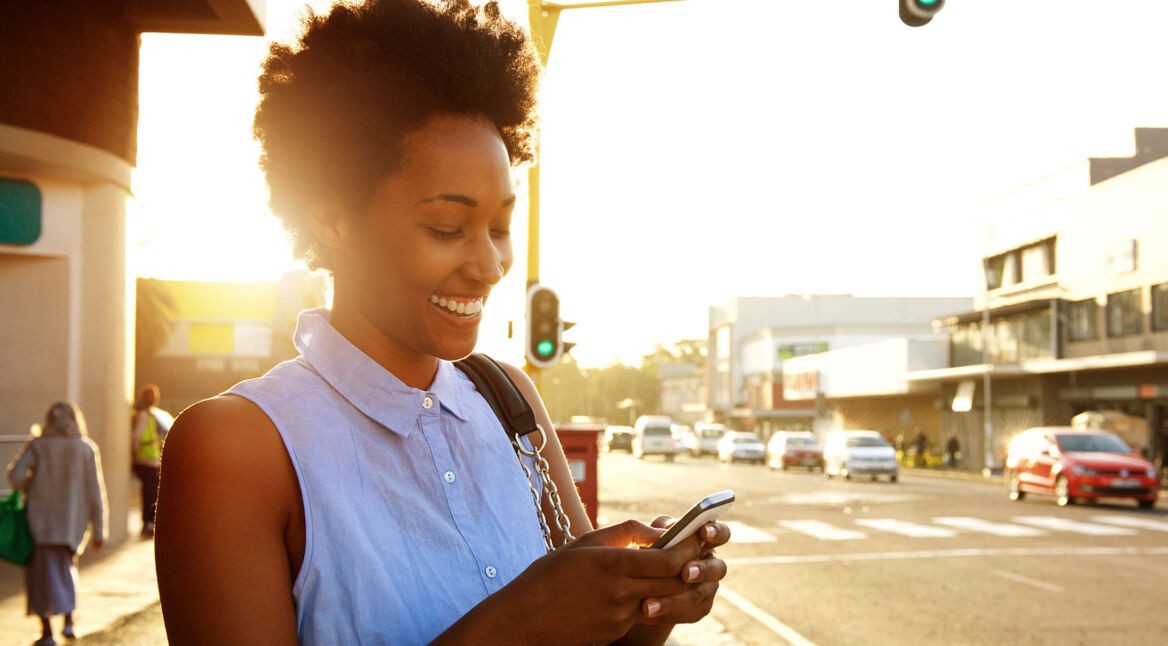 Frau mit Smartphone im Sonnenuntergang.