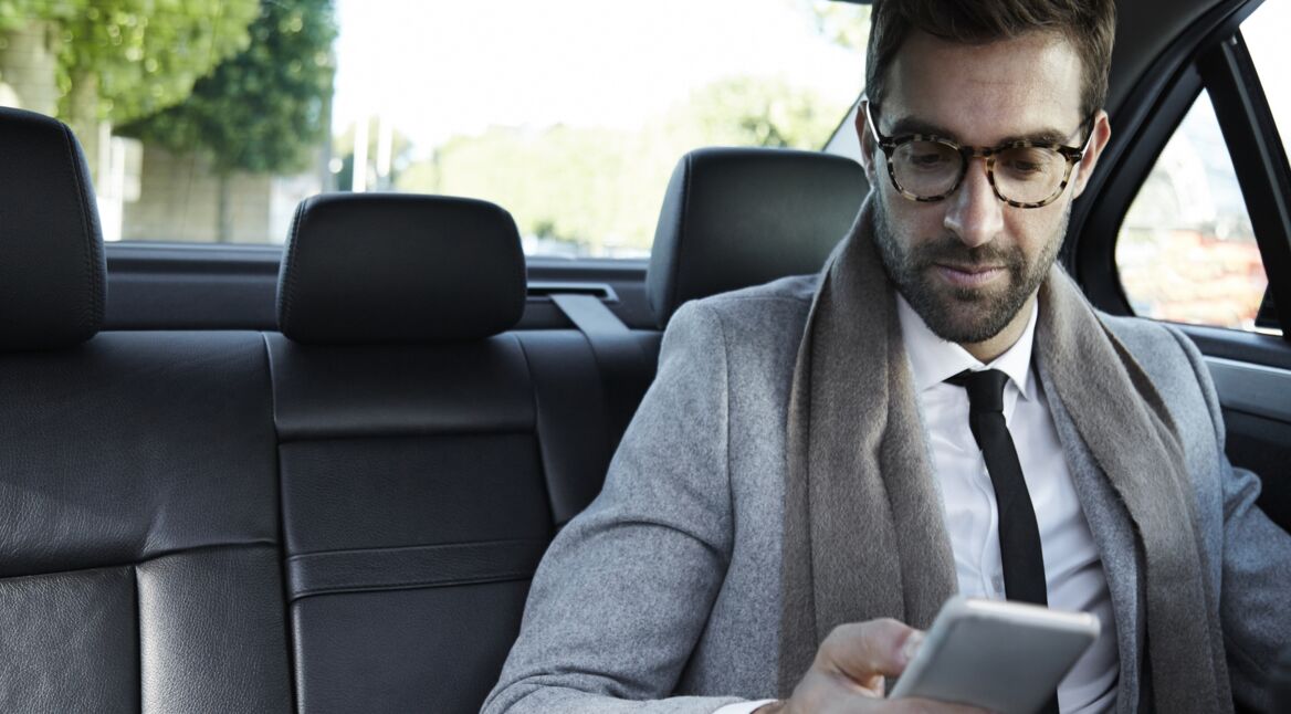 Geschäftsmann mit Smartphone im Auto