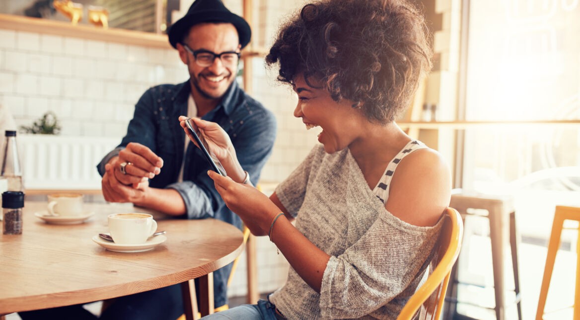 Cheerful woman using digital tablet with a friend at cafe