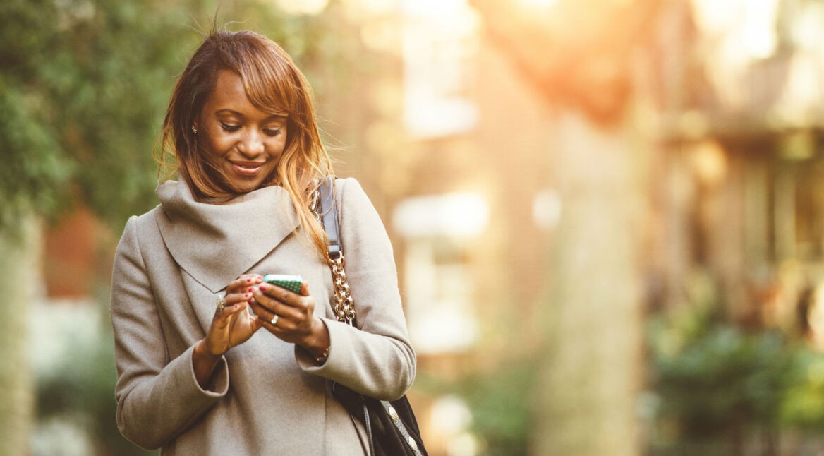 Junge Frau ist unterwegs mit ihrem Smartphone.