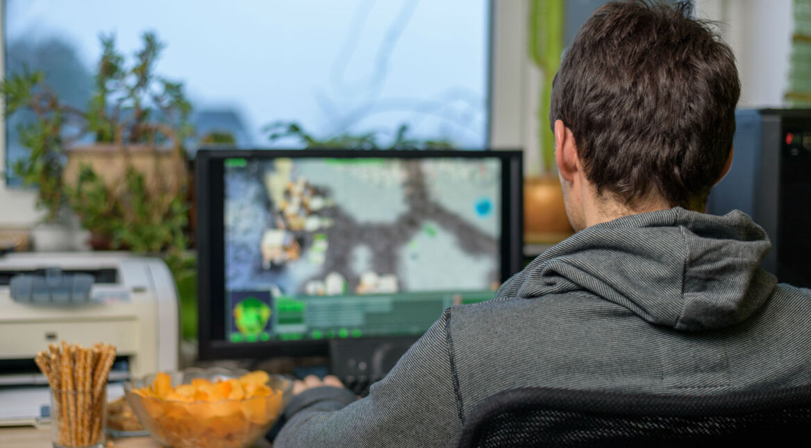 Junger Mann spielt Games am Computer.