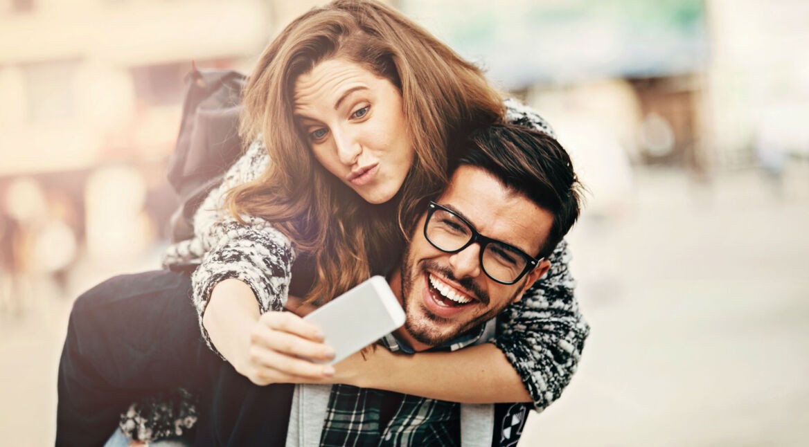 Junger Mann trägt Frau Huckepack.