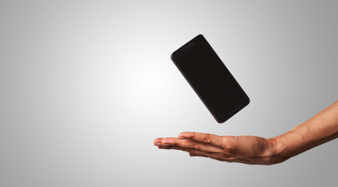 close-up of an open hand and a floating smart phone in isolated background