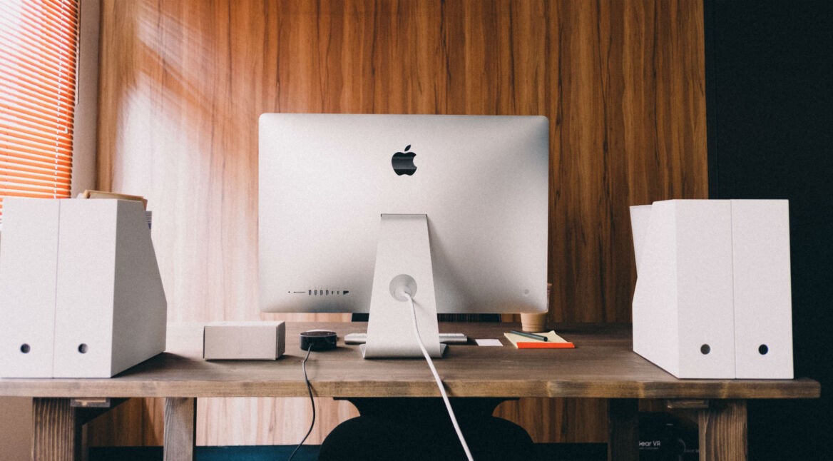 Ein Mac-PC in einem Büro mit hölzerner Wand.