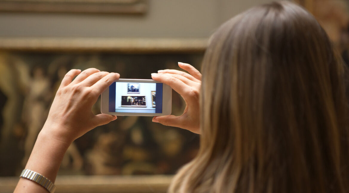 Kunstinteressierte Frau fotografiert ein Werk im Museum