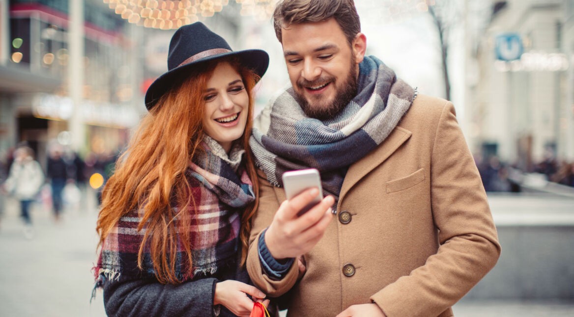 Junges Paar schaut auf ihr Smartphone.