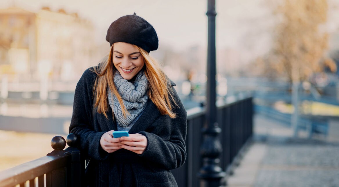 Frau mit iPhone auf Brücke