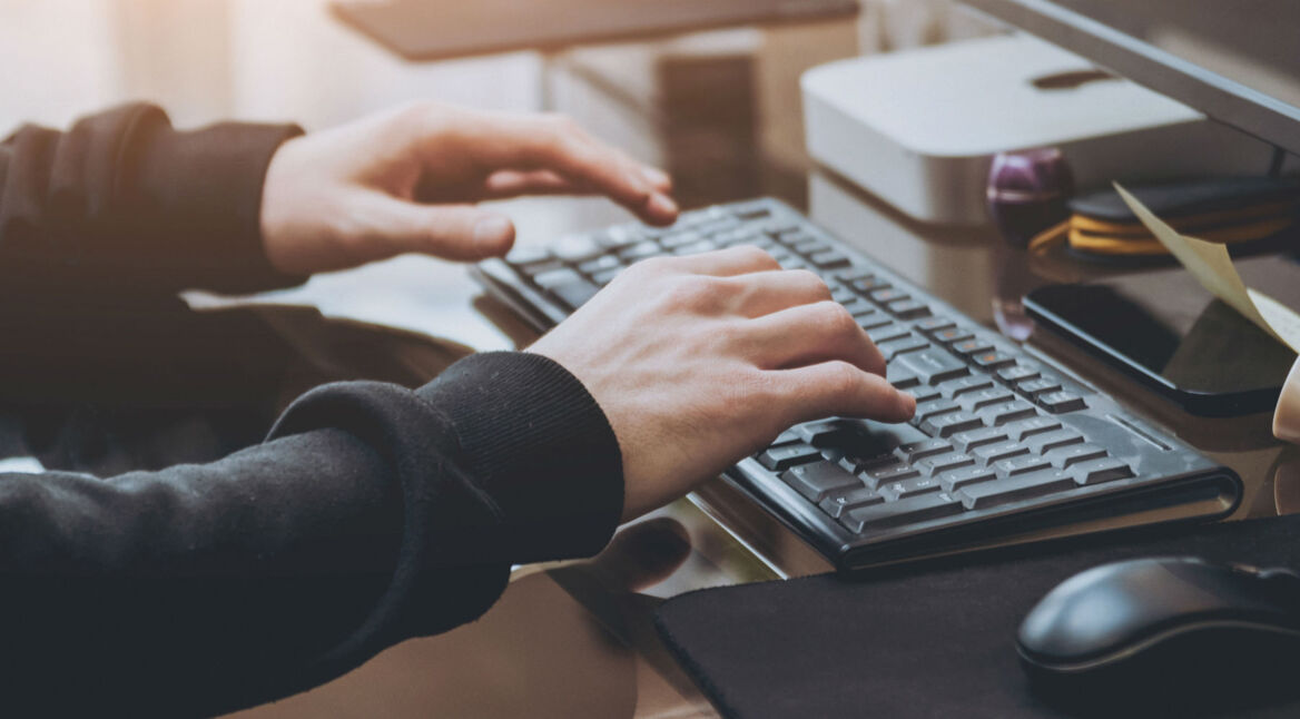 Junger Mann tippt am Computer.