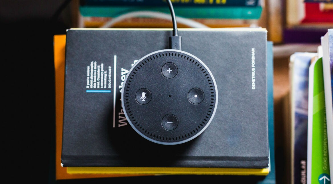 Amazon Echo Dot mit Alexa liegt auf einem Stapel Bücher.
