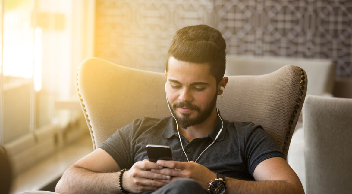 Junger Mann betrachtet entspannt Videos auf einem Smartphone