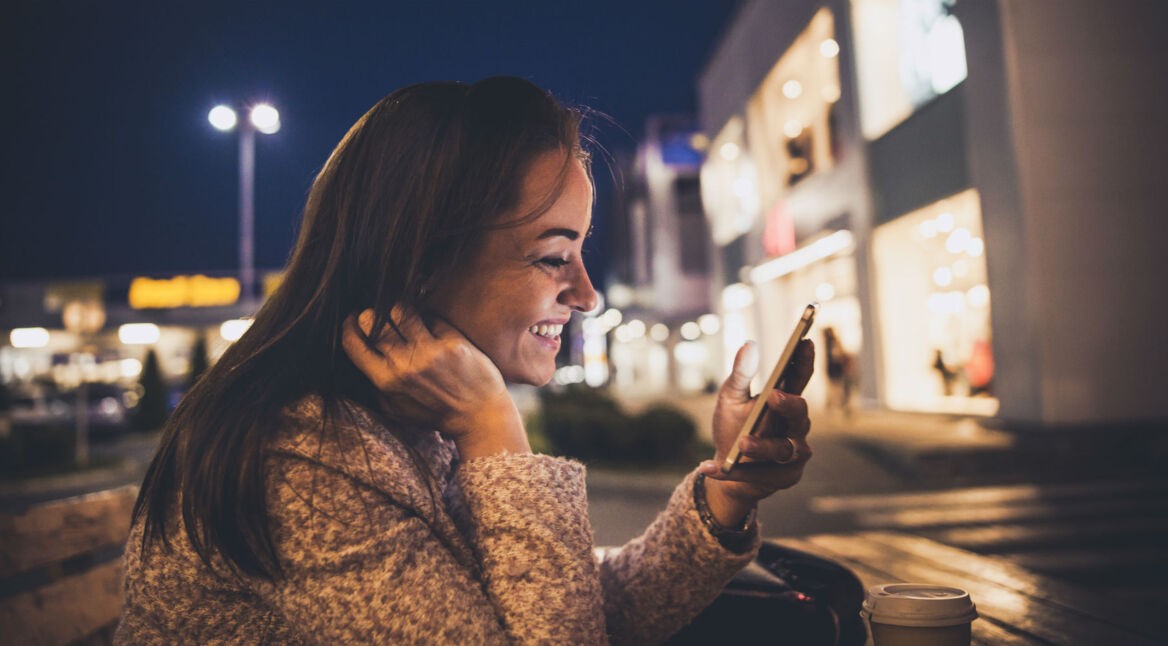Junge Frau checkt ihre Mails am Smartphone.
