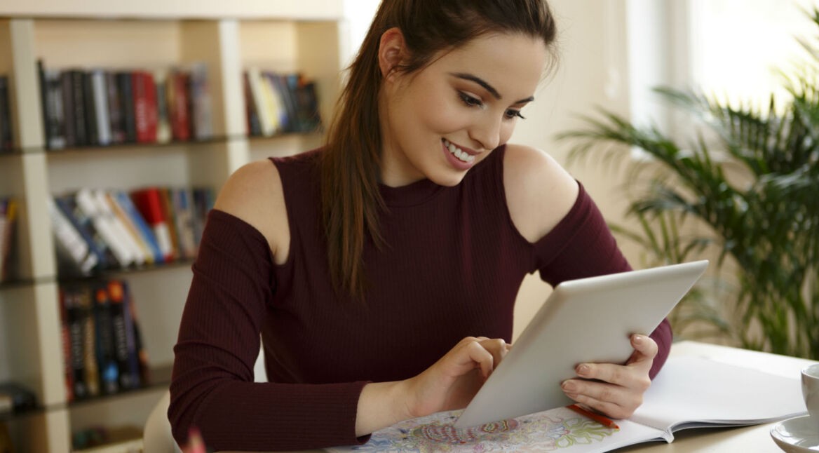 Eine junge Frau malt auf ihrem Tablet.