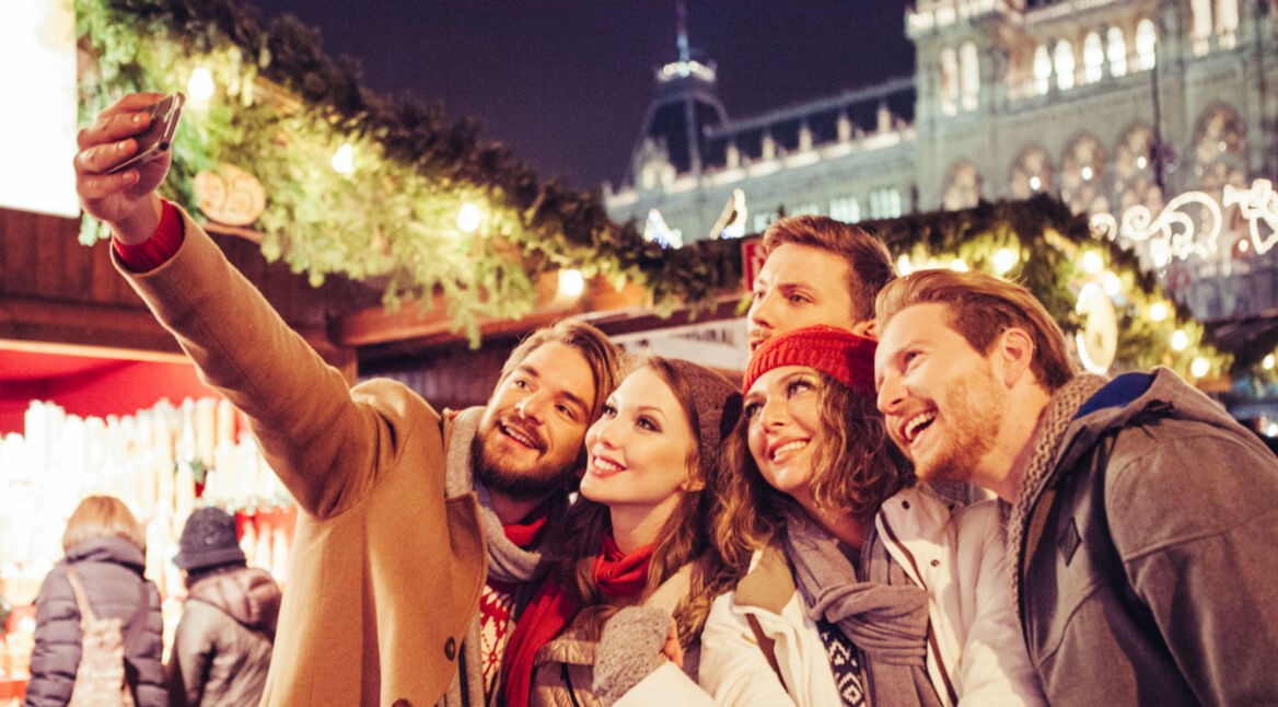 Freunde machen Selfie von sich auf einem Weihnachtsmarkt.