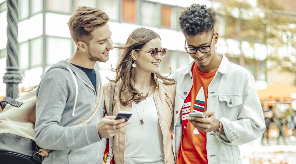 Freunde lachen und schauen auf ihre Smartphones.